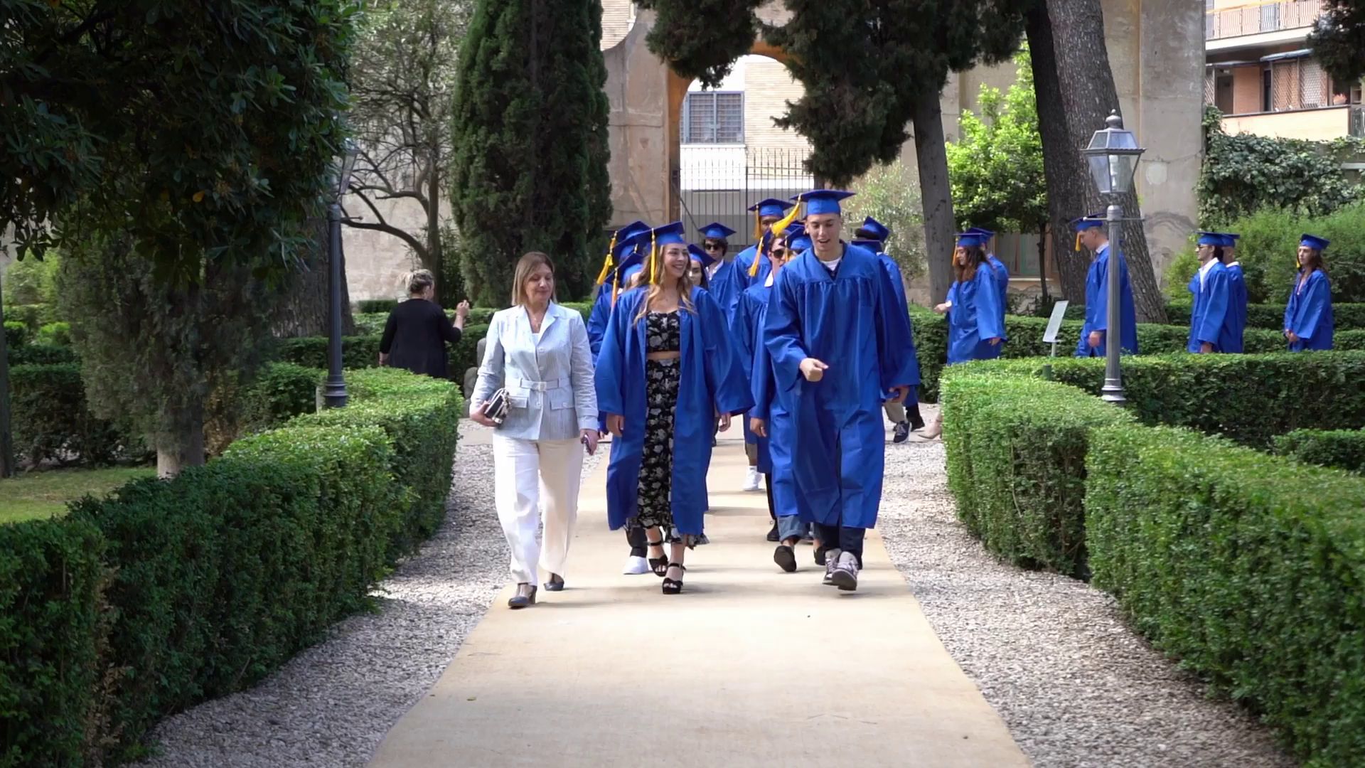 Rome City Institute graduate students in caps and gowns walking through the campus gardens